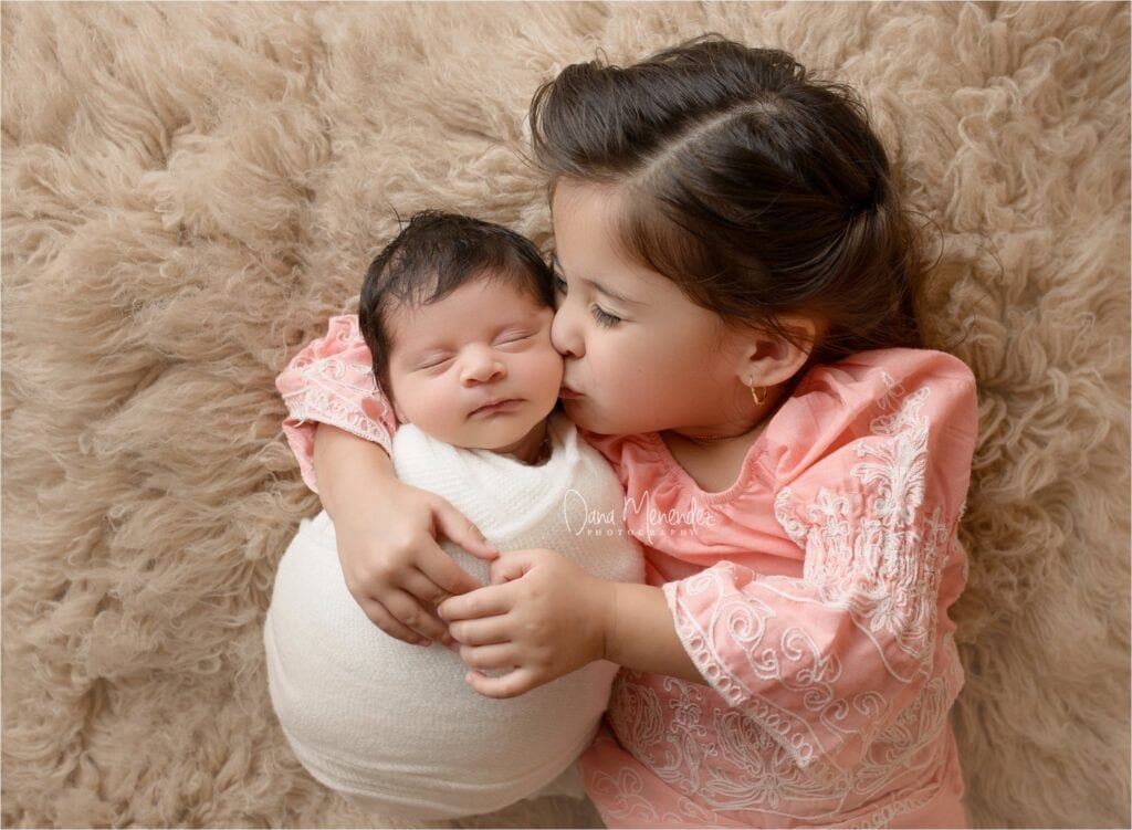 Newborn baby Fernando with older sister in a cozy, warm setting.