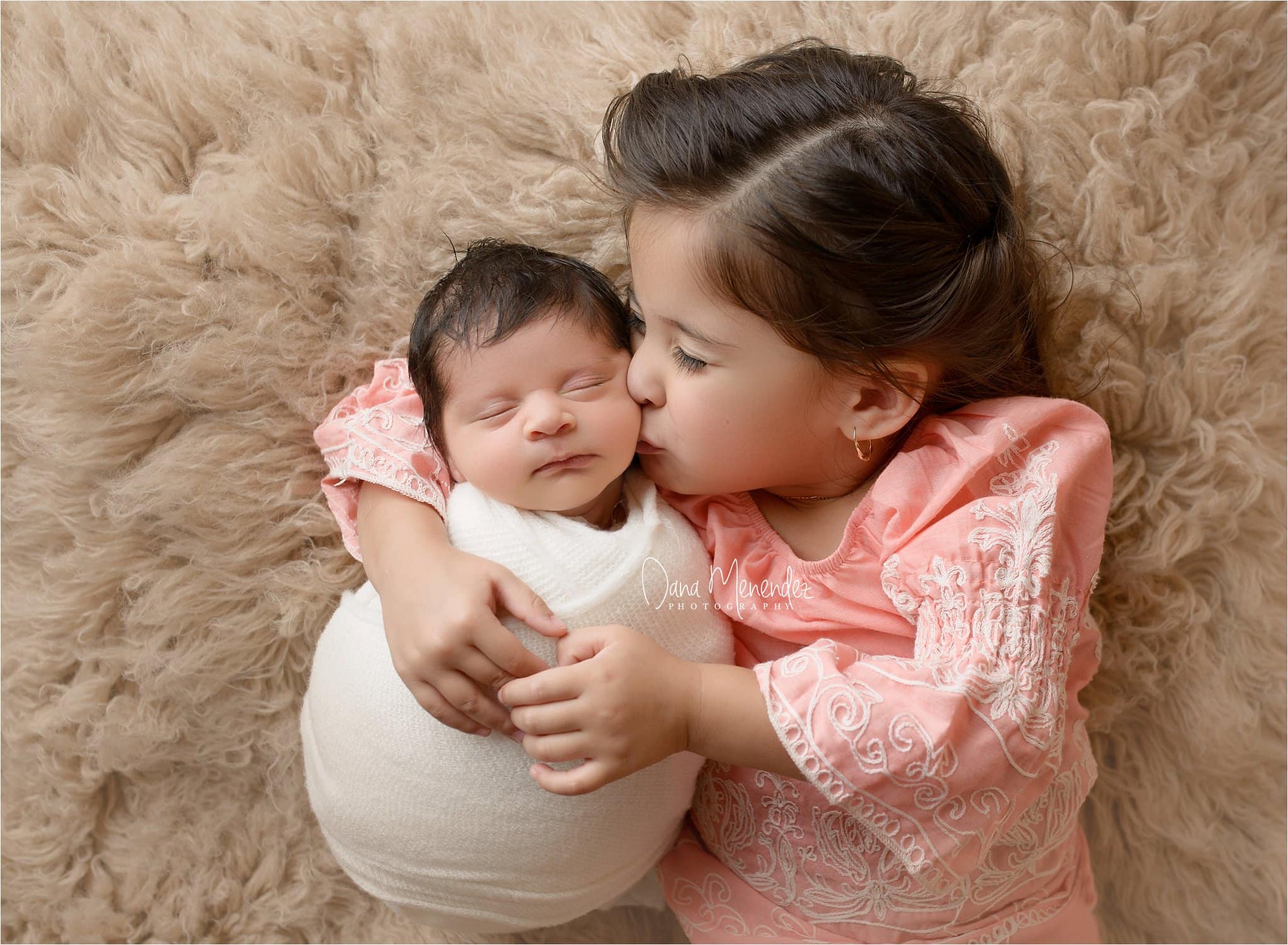Newborn baby Fernando with older sister in a cozy, warm setting.