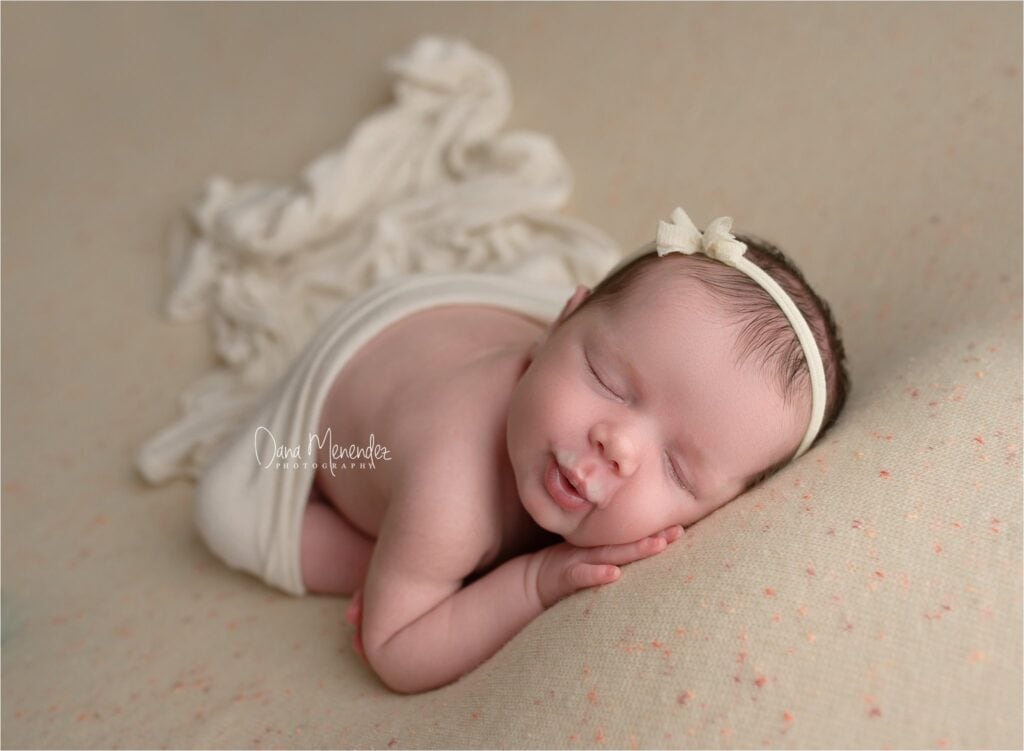 Adorable newborn girl peacefully sleeping on soft surface.