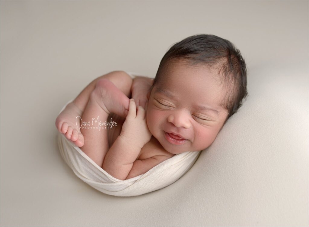 Adorable newborn baby peacefully sleeping in a soft wrap.