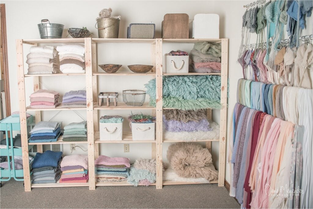 Soft pastel fabric and textile storage shelves in a cozy craft room.