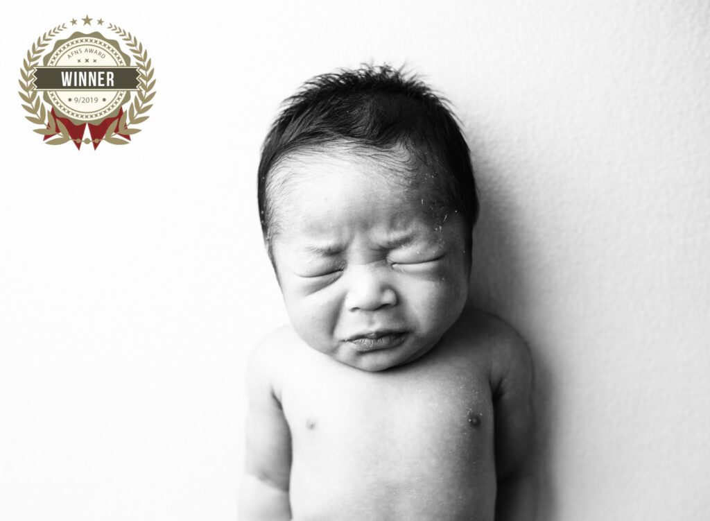 Baby crying newborn portrait in black and white, showcasing delicate features and emotional expressi.