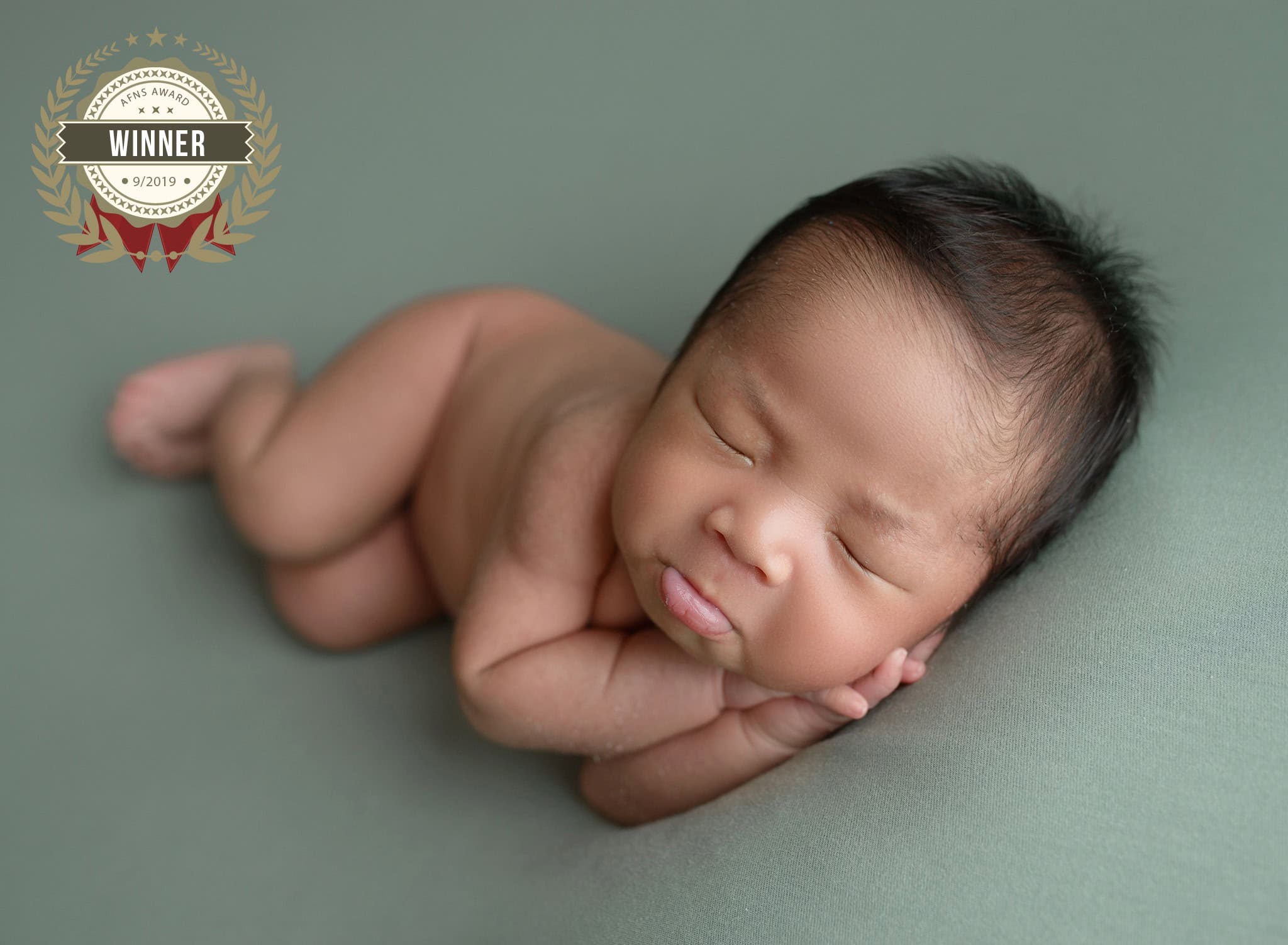Baby sleeping peacefully on a soft green surface.