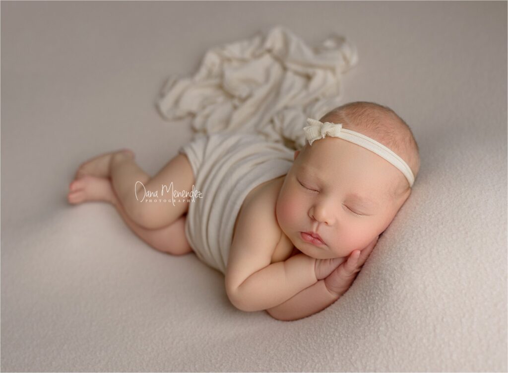 Baby sleeping peacefully on a soft surface with a headband and striped outfit.