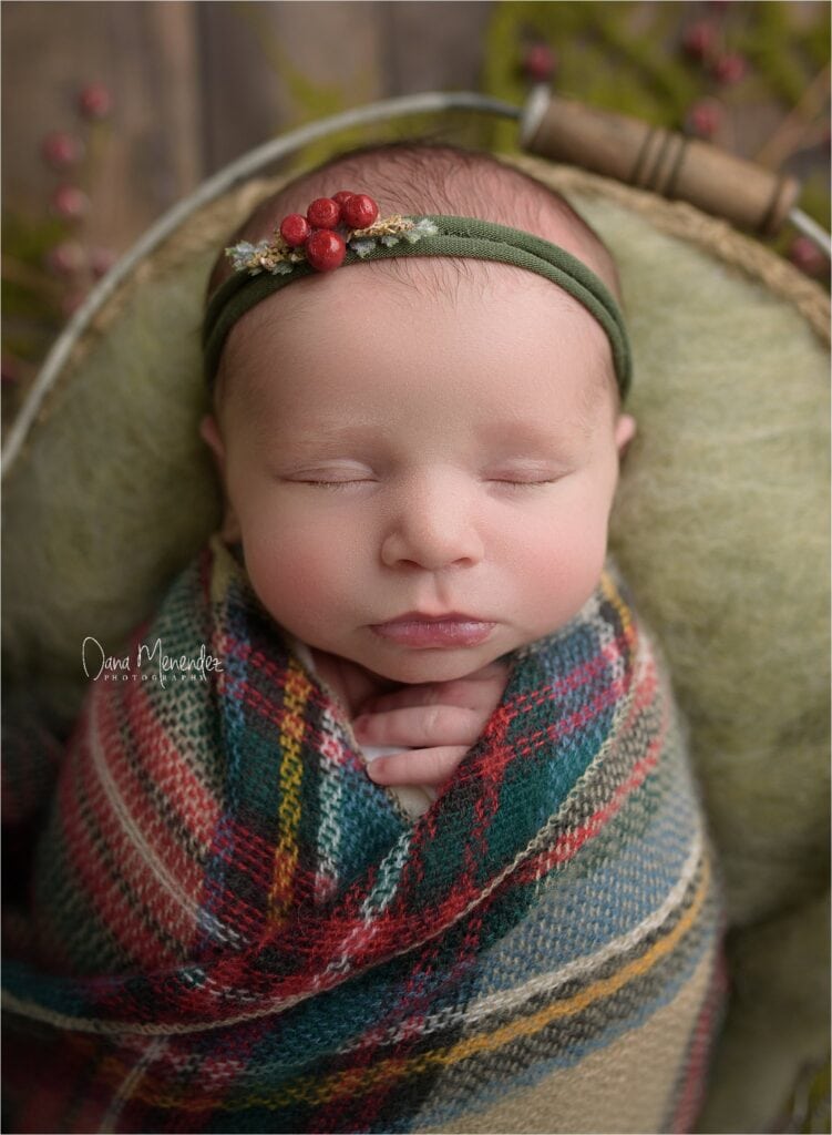 Baby sleeping peacefully with a holiday-themed headband and cozy blanket.