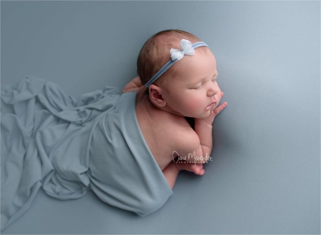 Adorable newborn girl sleeping peacefully on a soft blue blanket.