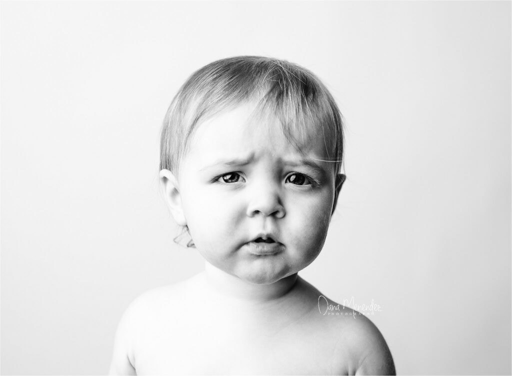 Baby's confused expression in black and white portrait.