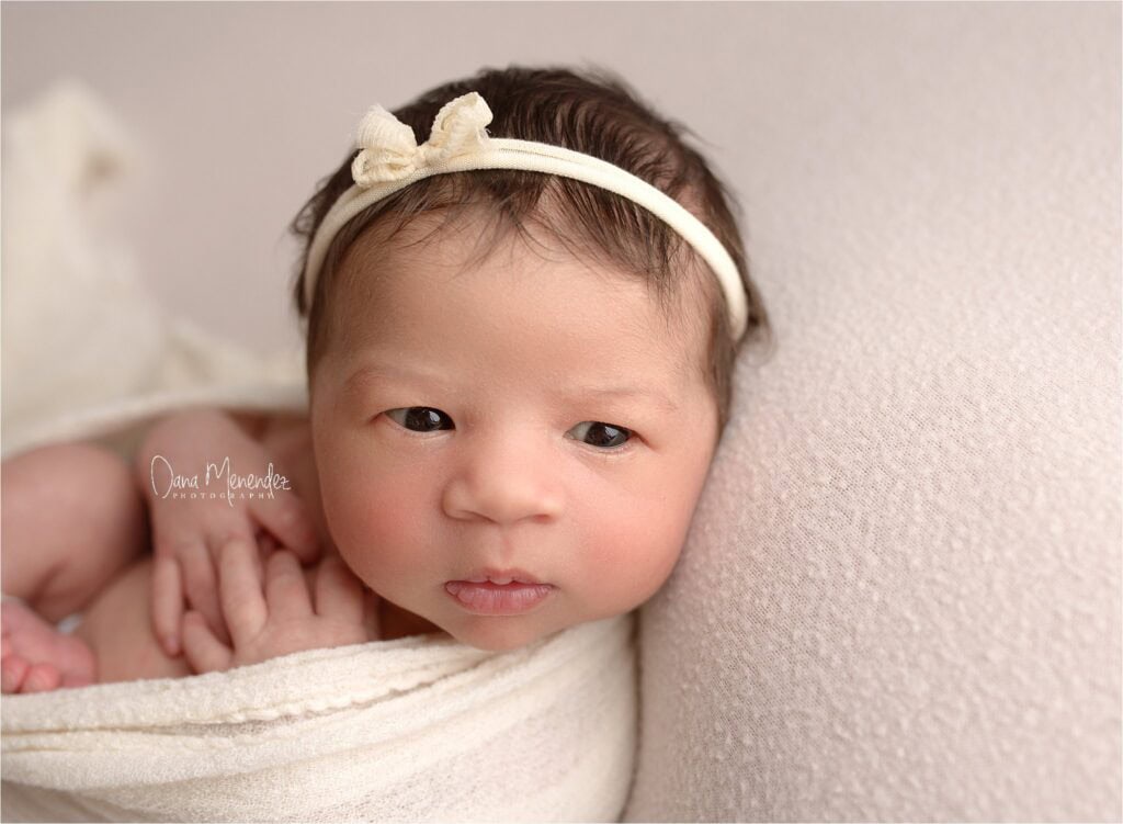 Newborn baby girl with headband, close-up portrait.