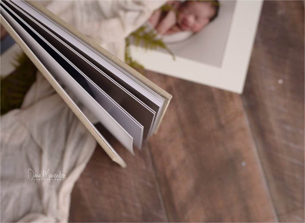 Newborn photo album with baby portrait on wooden floor.