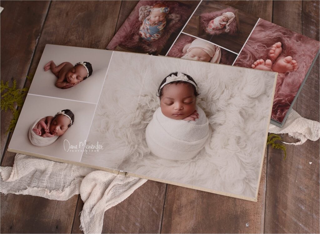 Newborn photo album featuring a sleeping baby girl with soft blankets and framed images.