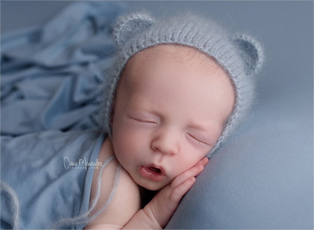 Newborn baby Parker sleeping peacefully, wearing a cozy gray hat, captured by Dana Menendez Photogra.