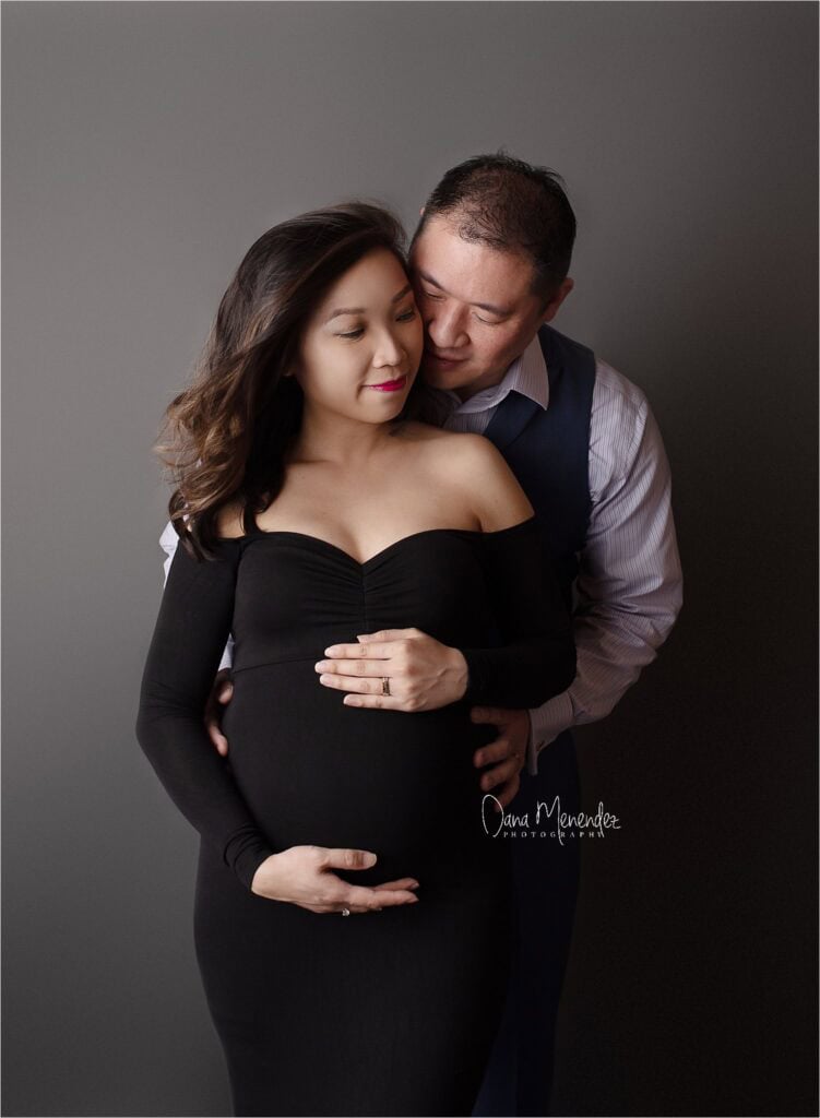 Pregnant woman with partner embracing her belly, celebrating pregnancy.