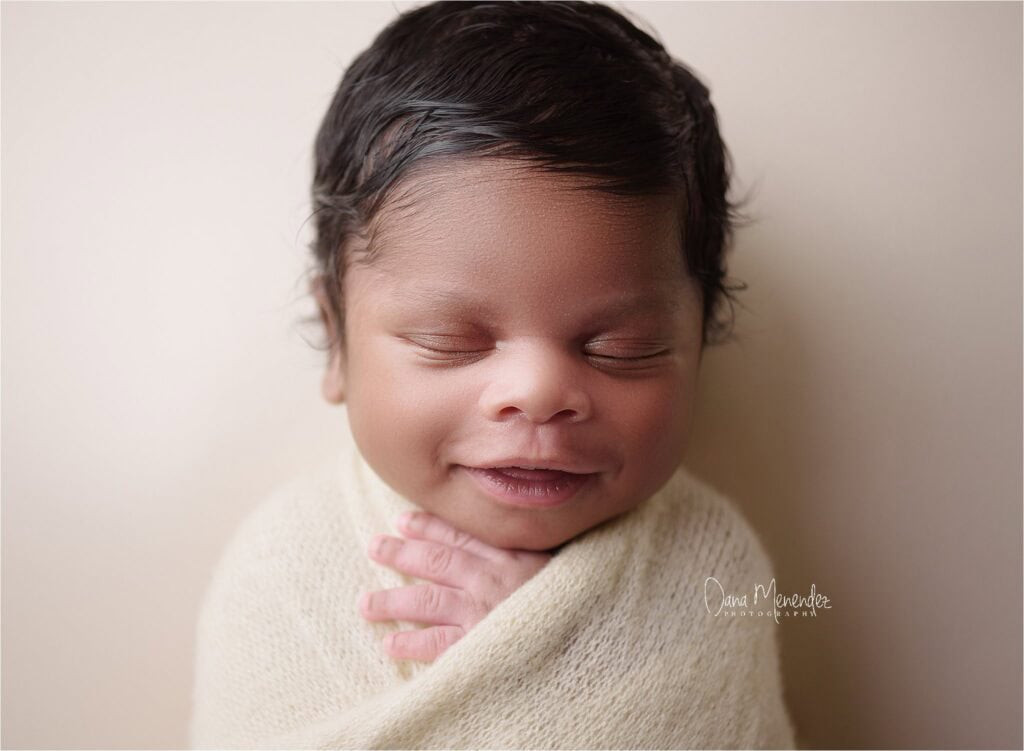 Adorable newborn sleeping peacefully wrapped in a cream blanket.