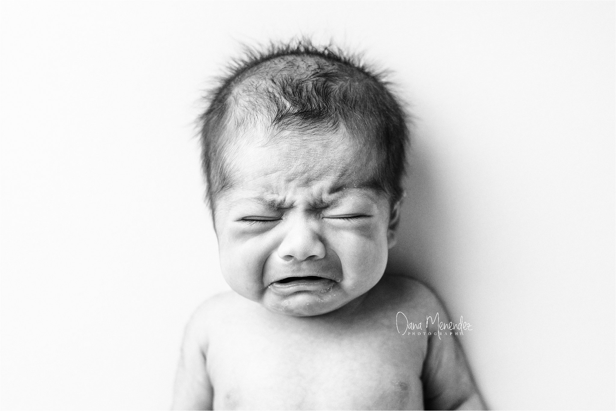 Newborn baby Maggie crying during her infant portrait session in Okotoks, AB.