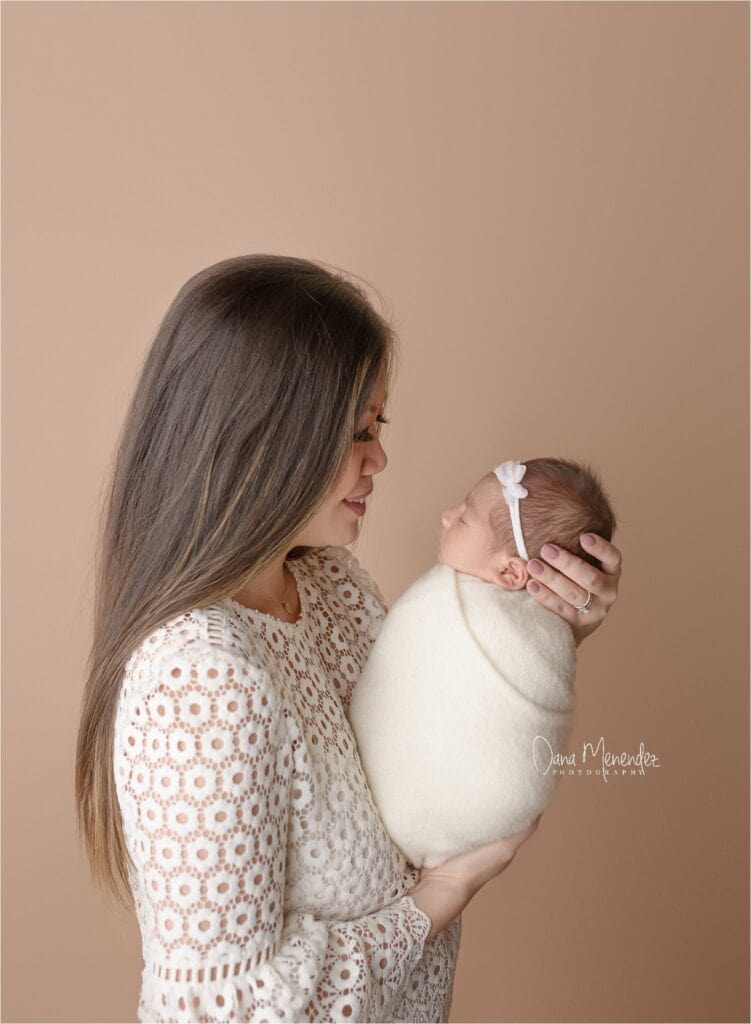 Adorable newborn Maggie held by her mother during a professional Okotoks photoshoot.