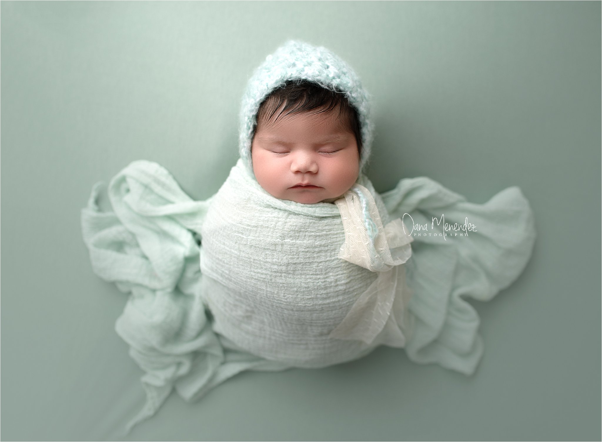 Newborn baby girl Isobella wrapped in soft white fabric, sleeping peacefully in a professional Okoto.