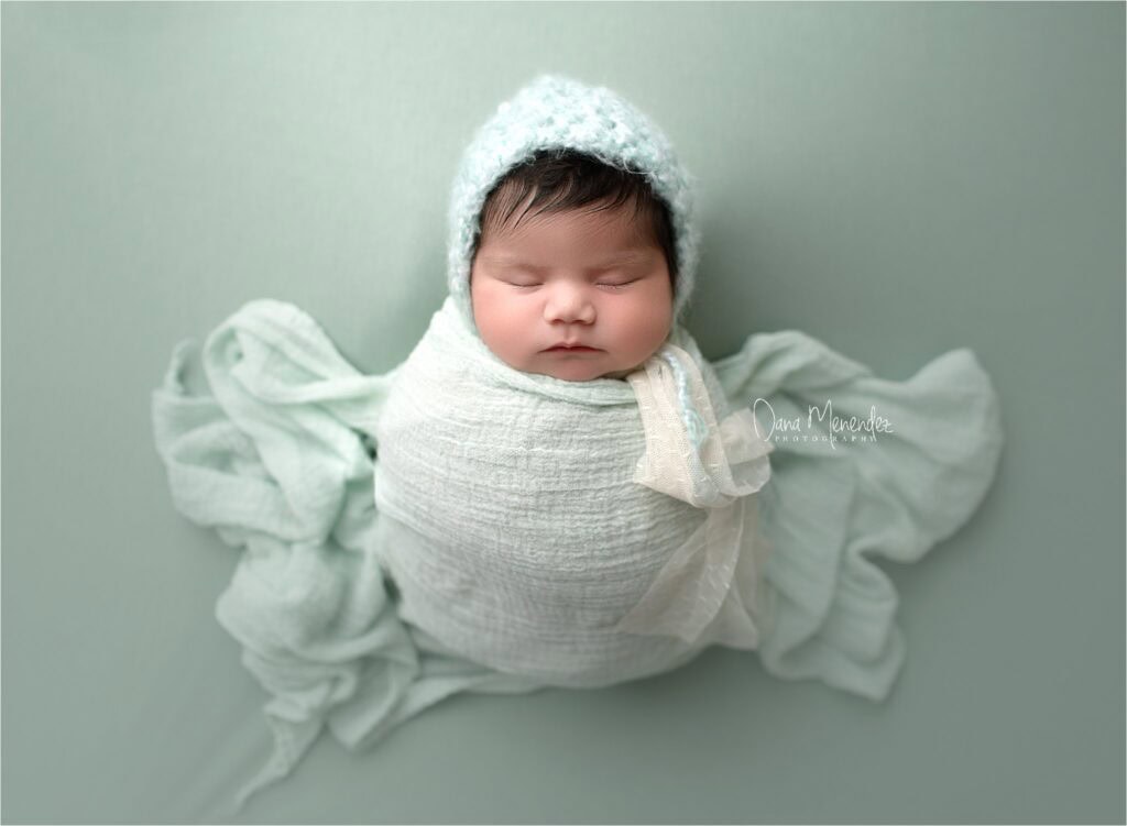 Newborn baby girl wrapped in soft white blanket with a cozy hat, peacefully sleeping in a profession.