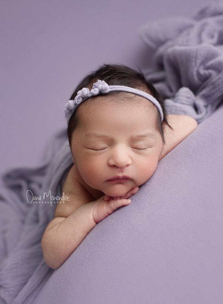Baby girl peacefully sleeping with a floral headband.