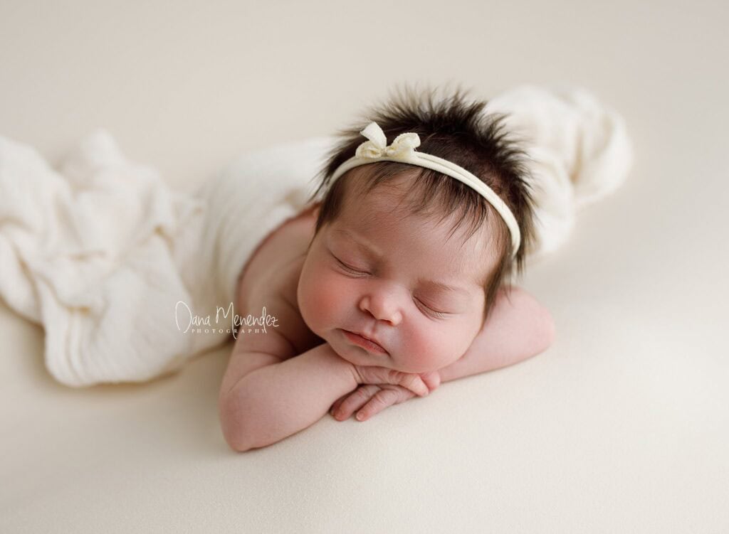 Adorable newborn girl peacefully sleeping with a headband.