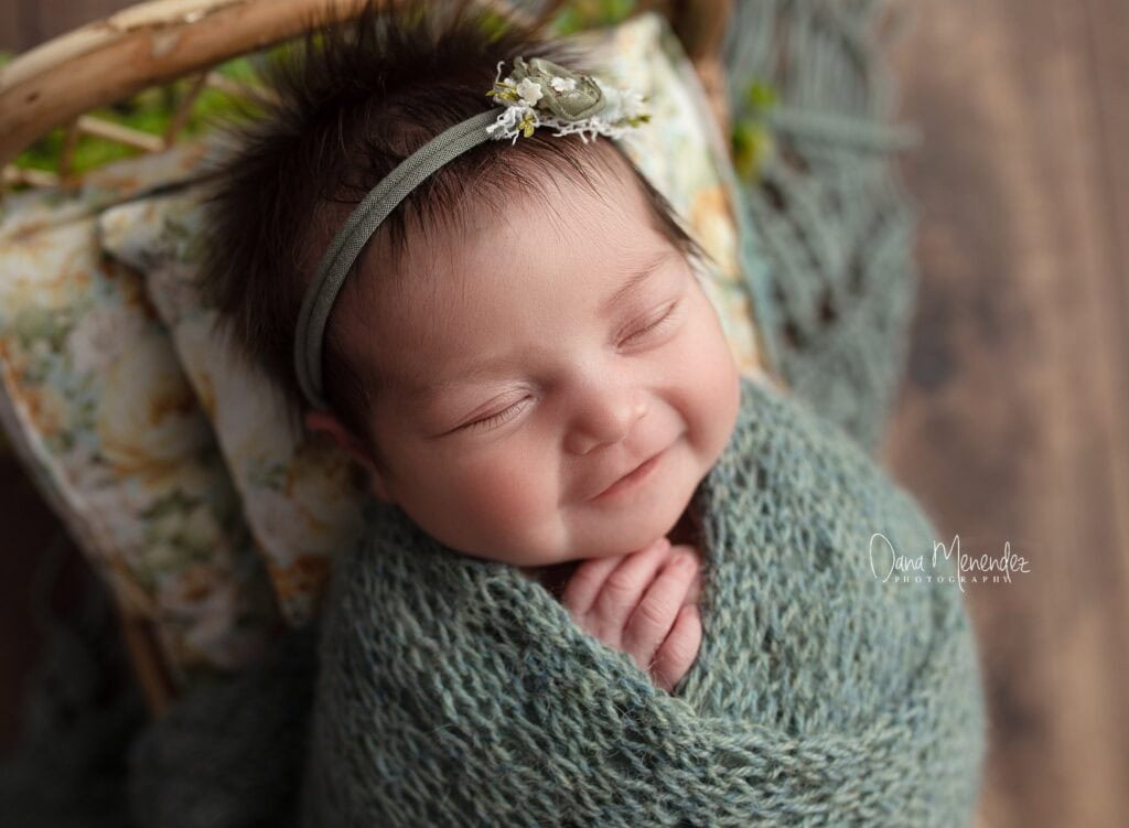 Baby girl peacefully sleeping wrapped in a green blanket.