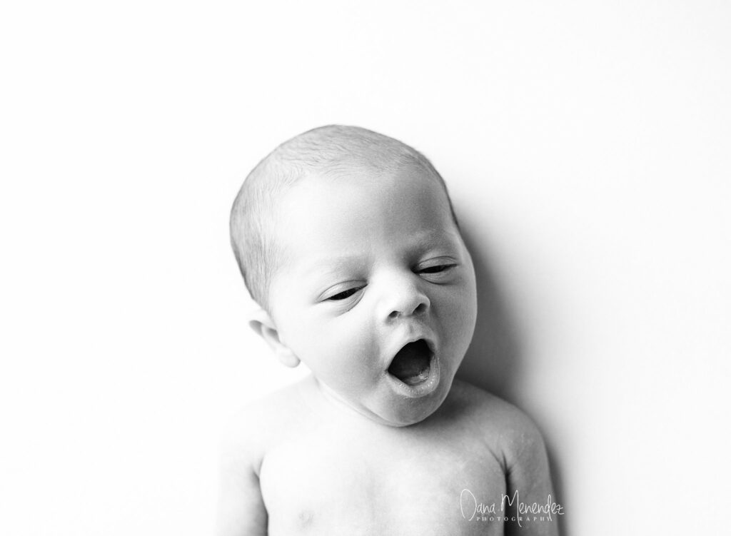 Adorable newborn baby yawning, black and white portrait.