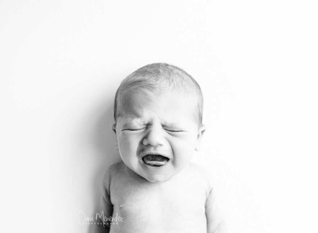 Baby crying, close-up in black and white, emotional expression.