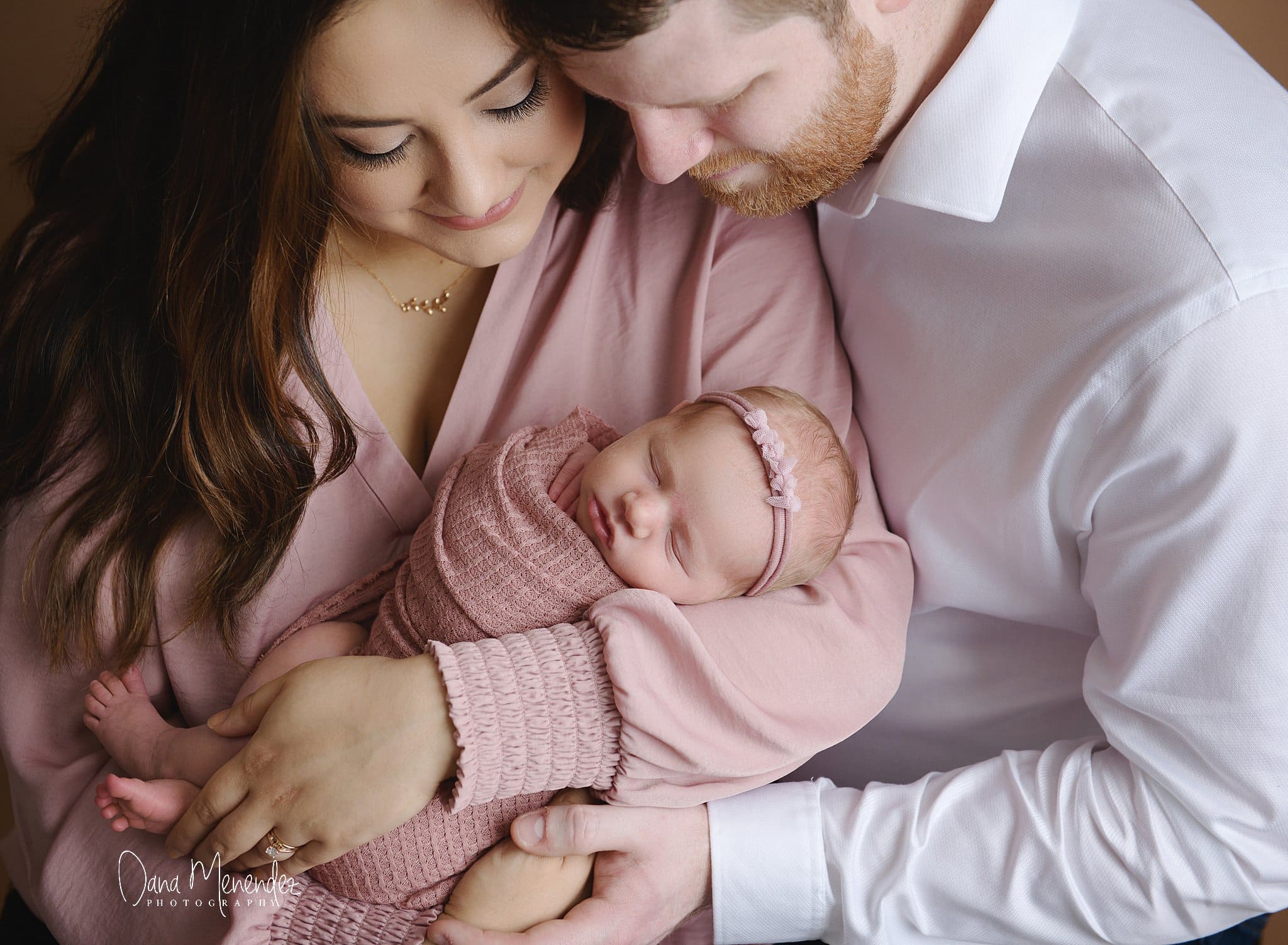 Baby sleeping peacefully with parents holding her gently.