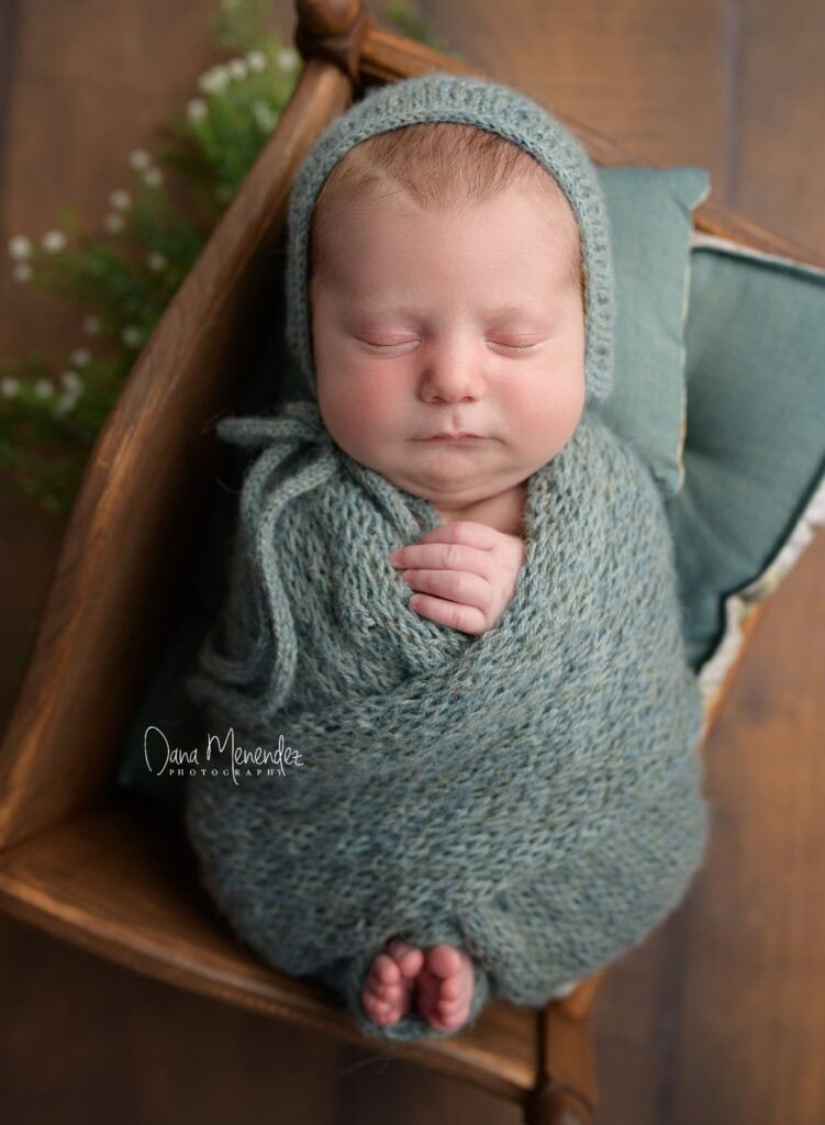 Newborn baby peacefully sleeping, wrapped in a cozy gray blanket with a matching bonnet.
