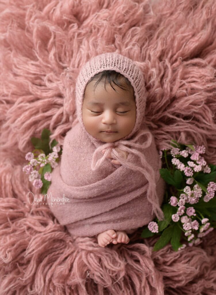 Baby girl peacefully sleeping in pink wrap and hat.