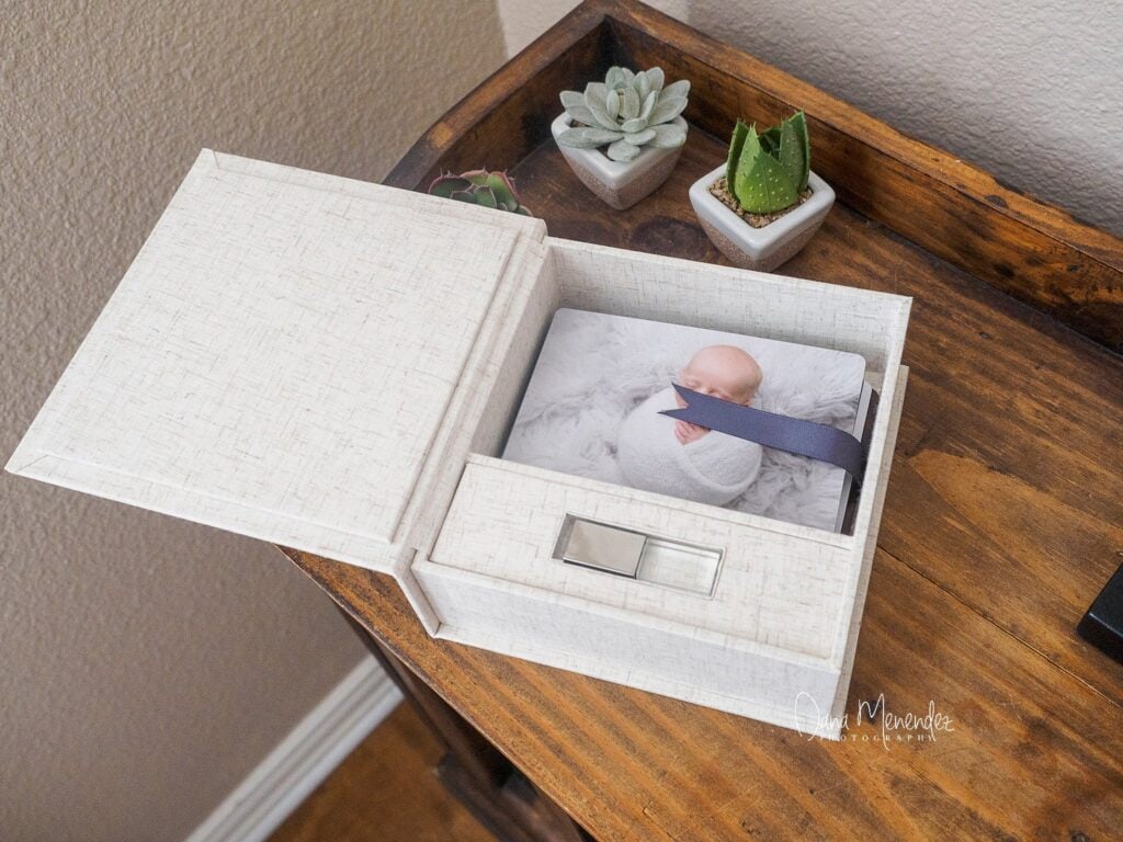 Newborn photo in a keepsake box on wooden table with succulents.