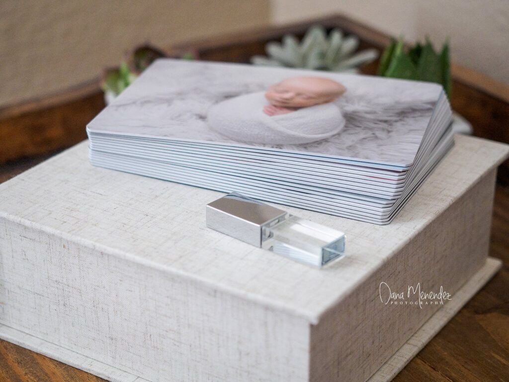Newborn photography portfolio book on a white textured surface.