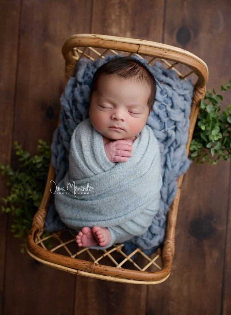 Baby sleeping peacefully in a wicker basket with a cozy blanket.