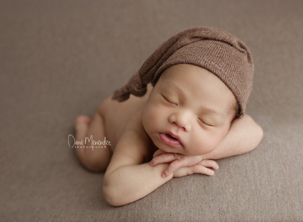 Adorable newborn baby sleeping peacefully with a brown hat.