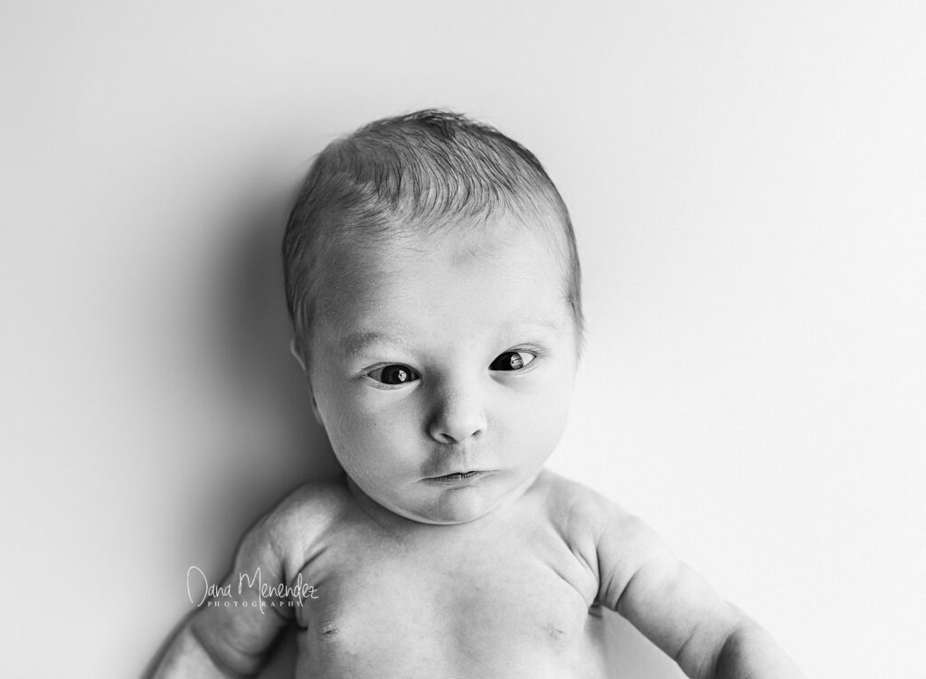 Baby newborn portrait in black and white, showcasing delicate features and peaceful expression.