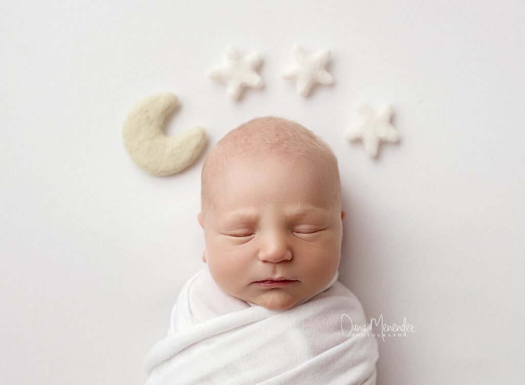 Baby sleeping peacefully with moon and star decorations in the background.