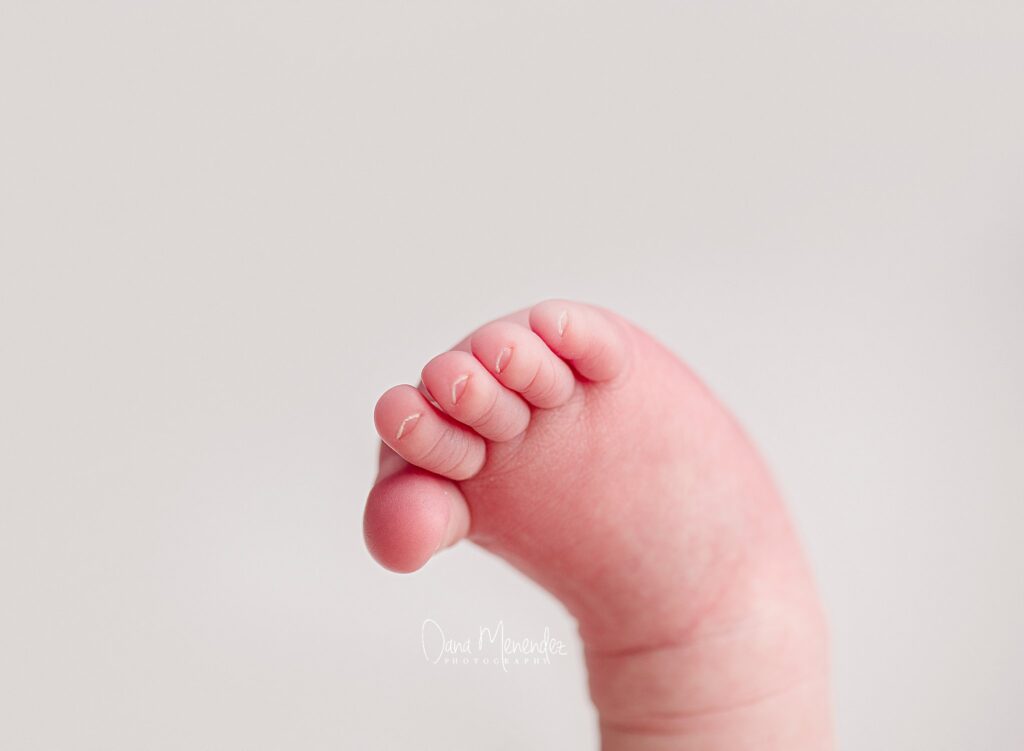 Close-up of a newborn baby's tiny hand gripping a finger.