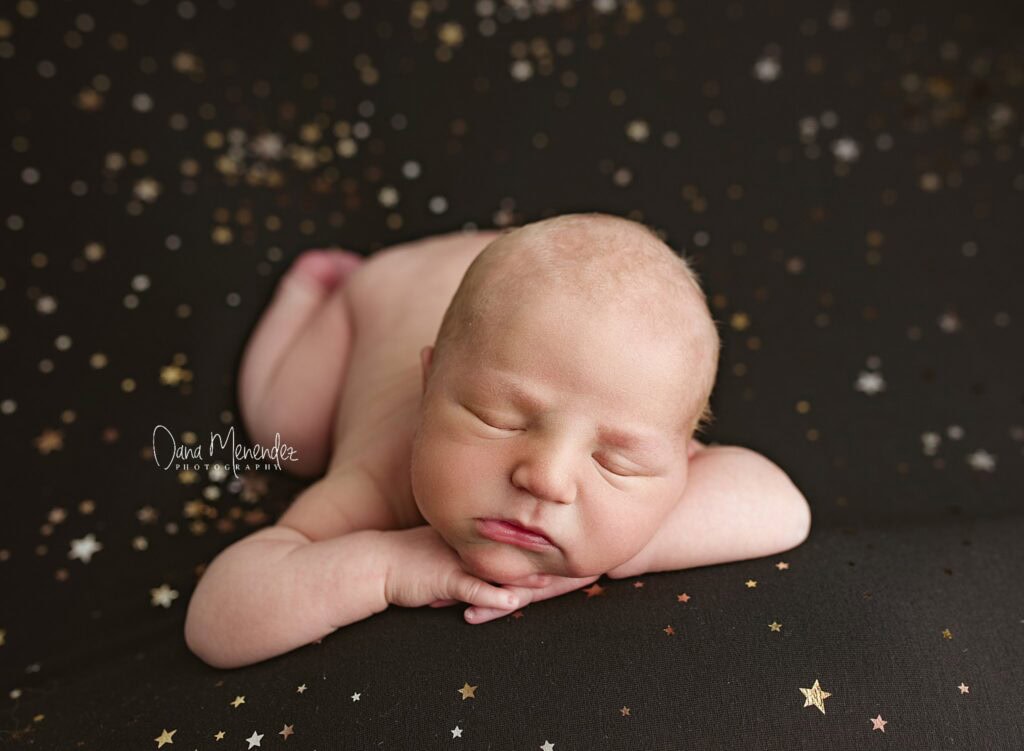 Adorable sleeping newborn baby with soft background and star confetti.