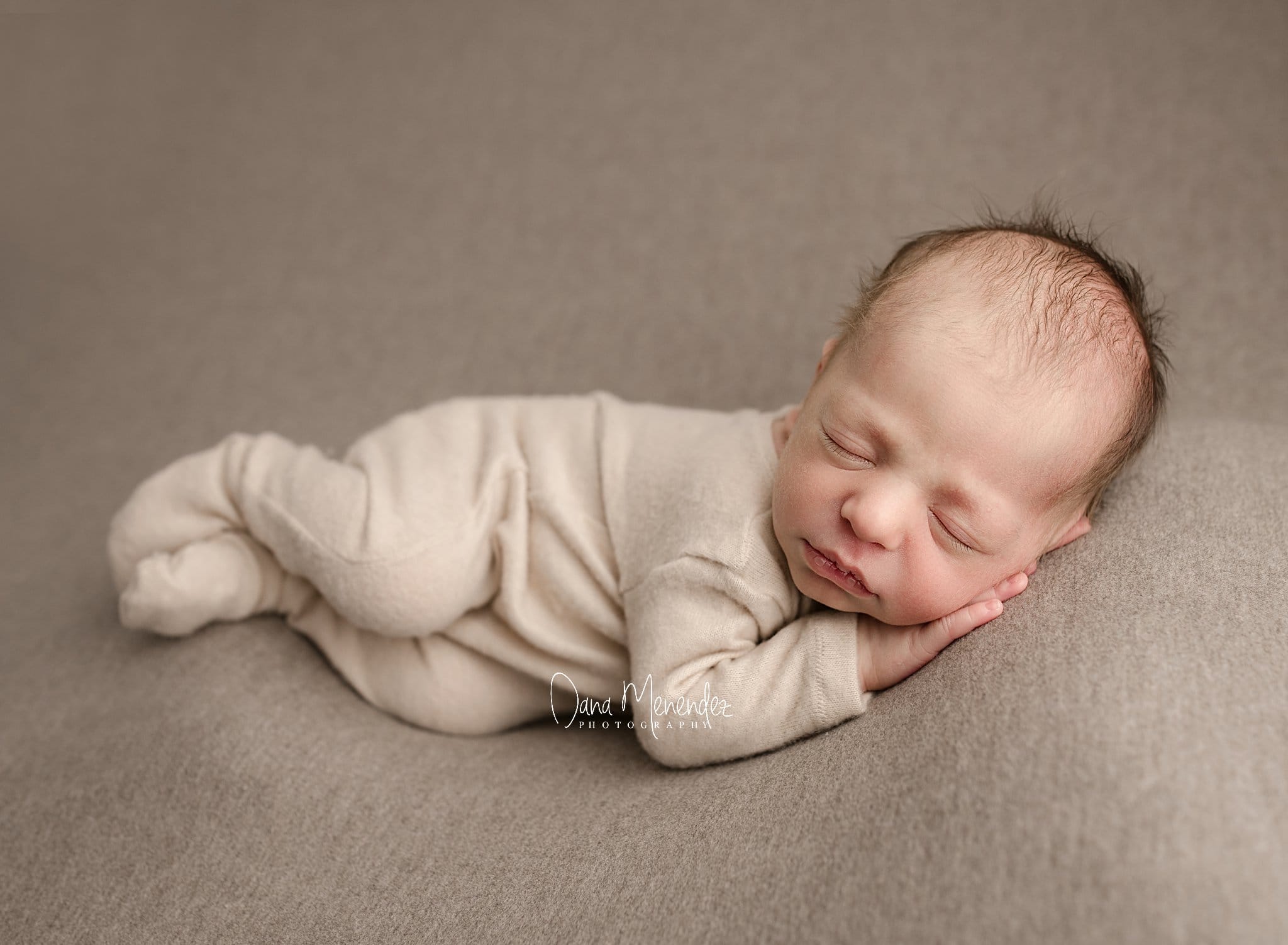 Baby sleeping peacefully on a soft gray blanket.