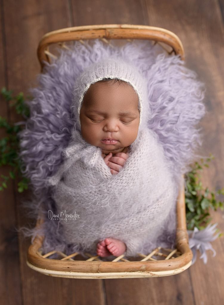 Adorable newborn baby wrapped in soft gray blanket, peacefully sleeping in a cozy basket.