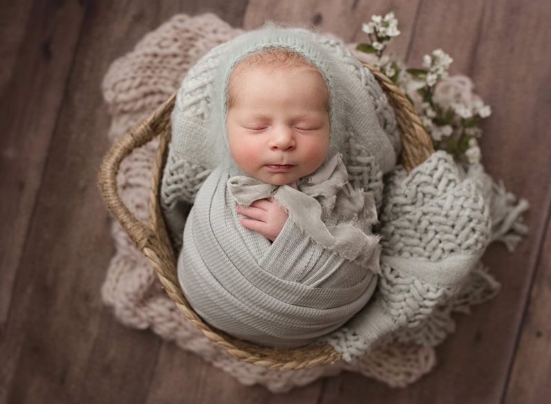 Adorable newborn baby peacefully sleeping in a basket with cozy blankets in calgary ab