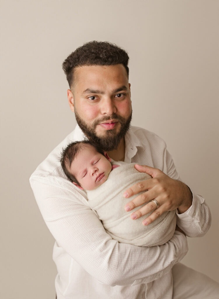 Father holding sleeping newborn baby in his arms.