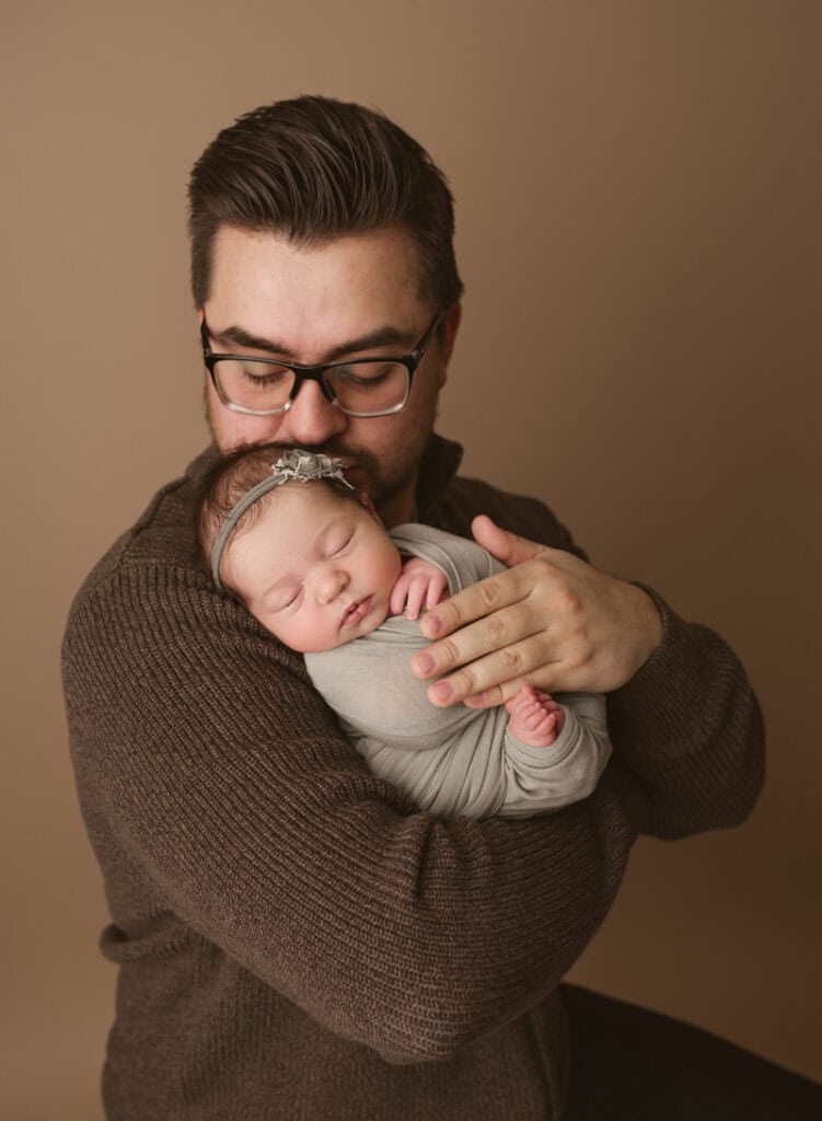 Heartwarming newborn portrait with father holding baby gently.