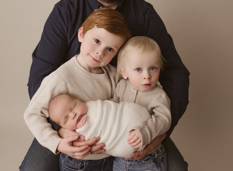 Family holding newborn baby, portrait in Okotoks, Alberta.
