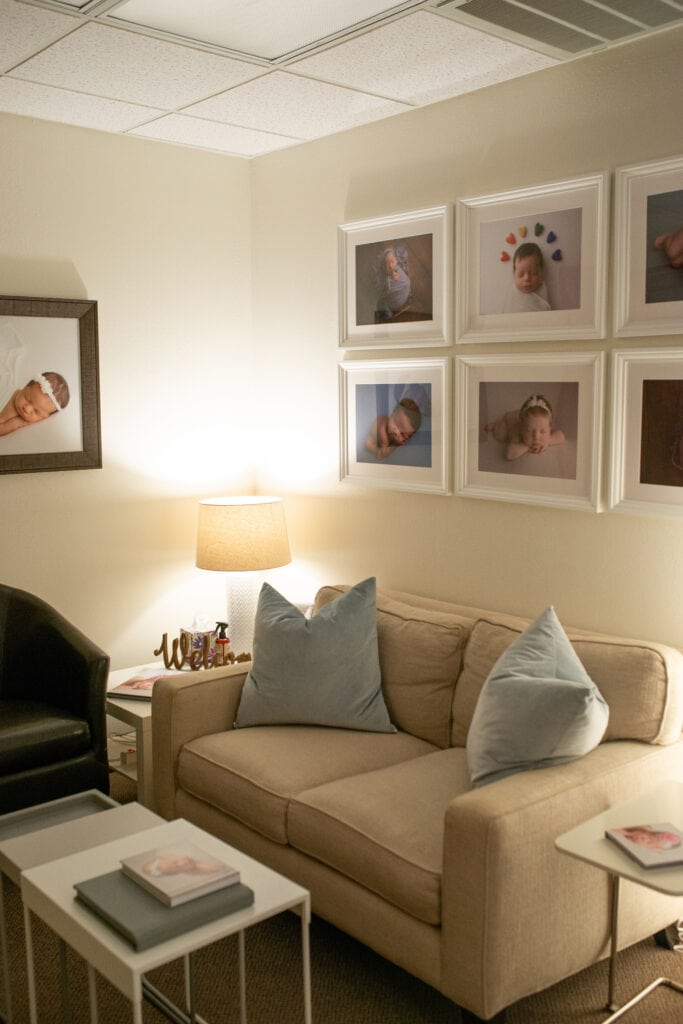 Cozy newborn photography studio with framed baby portraits on the wall.