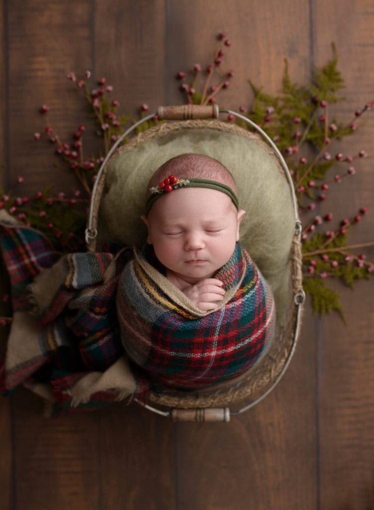 Baby girl sleeping in a plaid wrap with festive headband.